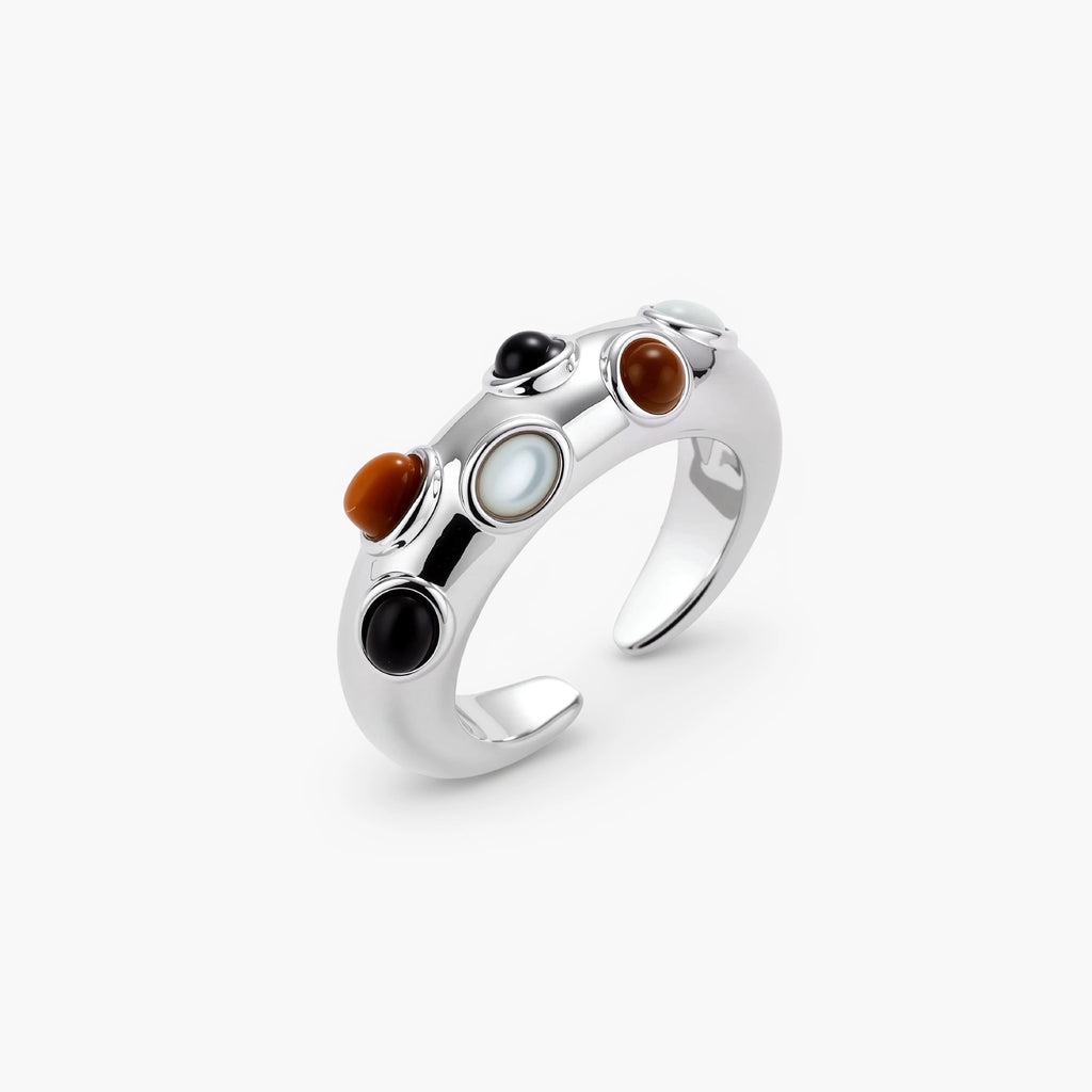 Adjustable platinum-plated ring with multiple oval cabochon stones in black, amber, and white tones on neutral background.