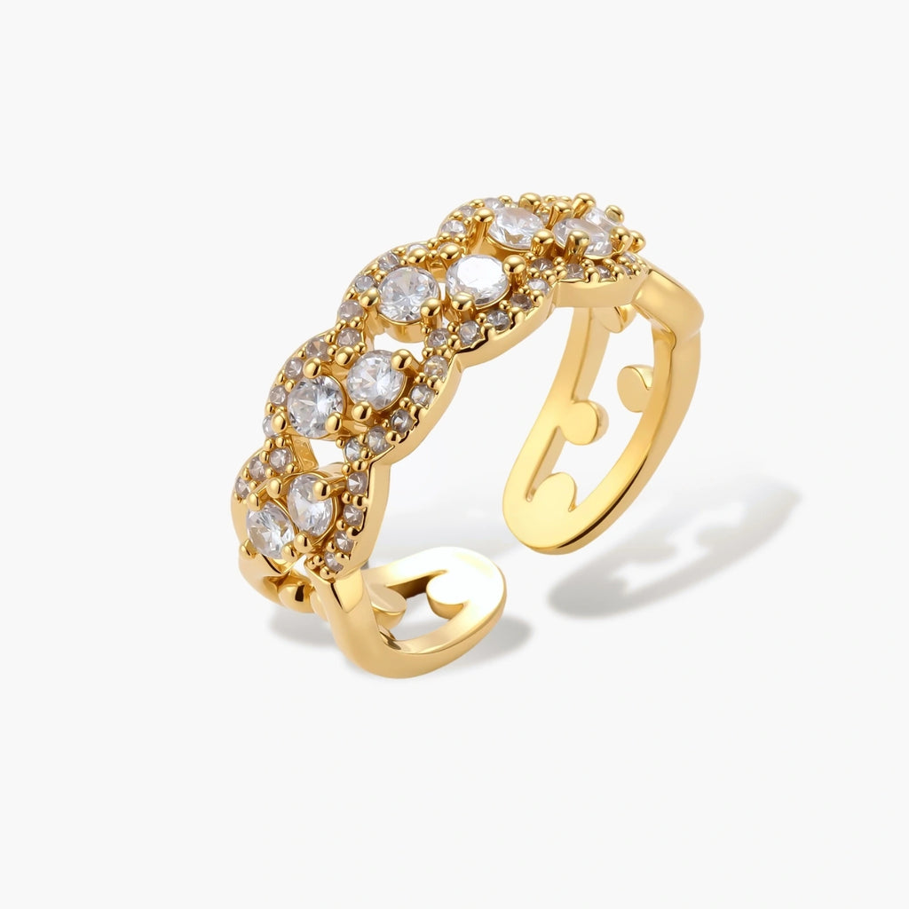 Adjustable gold-plated ring with multiple crystal clusters in intricate chain design on cream background.