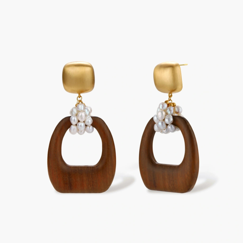 Gold-plated stud earrings with pearl clusters and organic brown wooden hoops on cream background