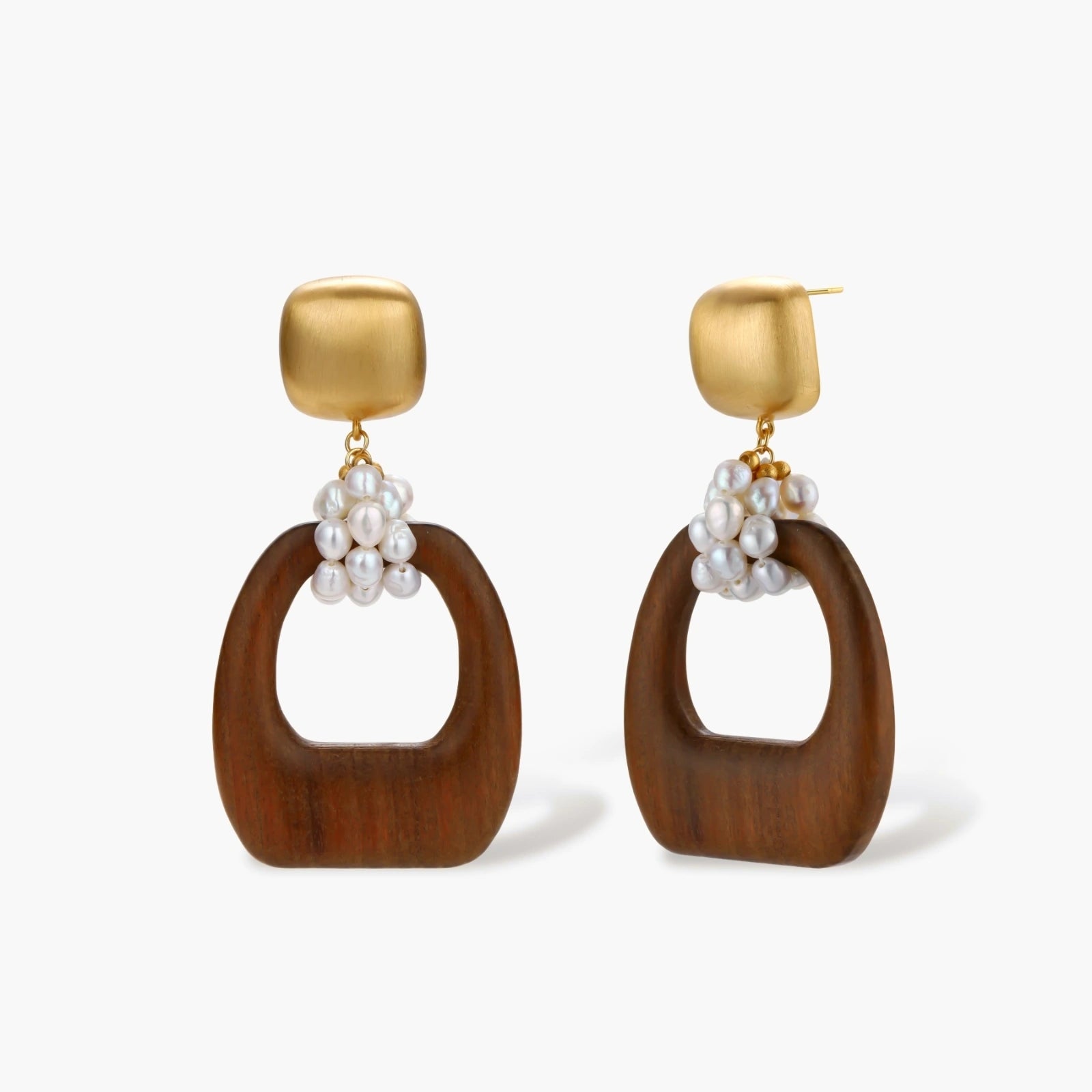 Gold-plated stud earrings with pearl clusters and organic brown wooden hoops on cream background