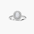 Sterling silver ring with oval moissanite center stone surrounded by double halo of sparkling stones on neutral background.
