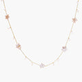 Gold vermeil chain with iridescent star-shaped baroque pearls and small round freshwater pearl drops on cream background.