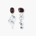 Abstract sculptural silver earrings with brown resin stones featuring organic fluid metalwork design on white background.