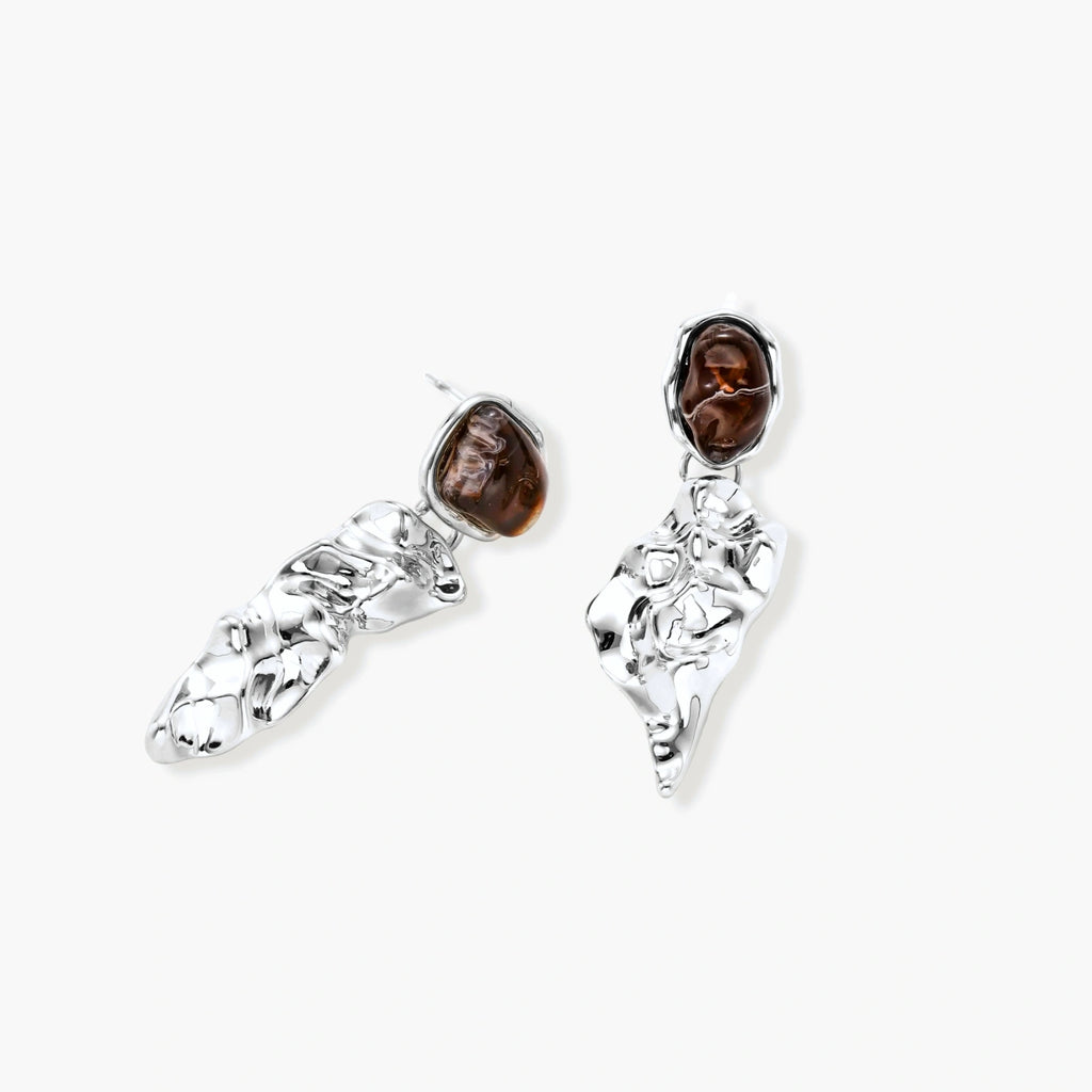 Abstract sculptural silver earrings with brown resin stones featuring organic fluid metalwork design on white background.