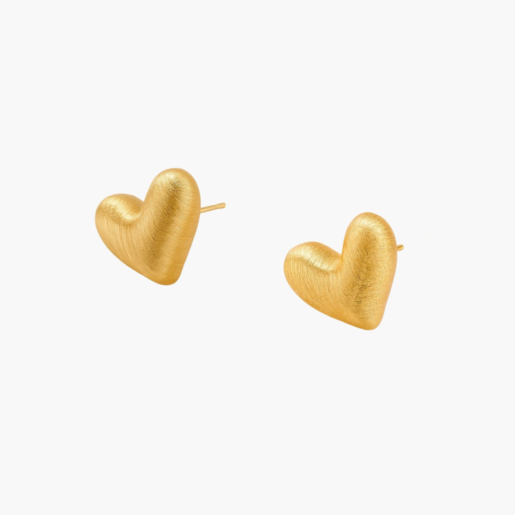 Pair of small heart-shaped stud earrings with brushed metallic finish, showing both silver and gold variants on neutral background.