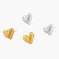 Pair of textured heart-shaped stud earrings in brushed platinum-plated sterling silver against cream background.