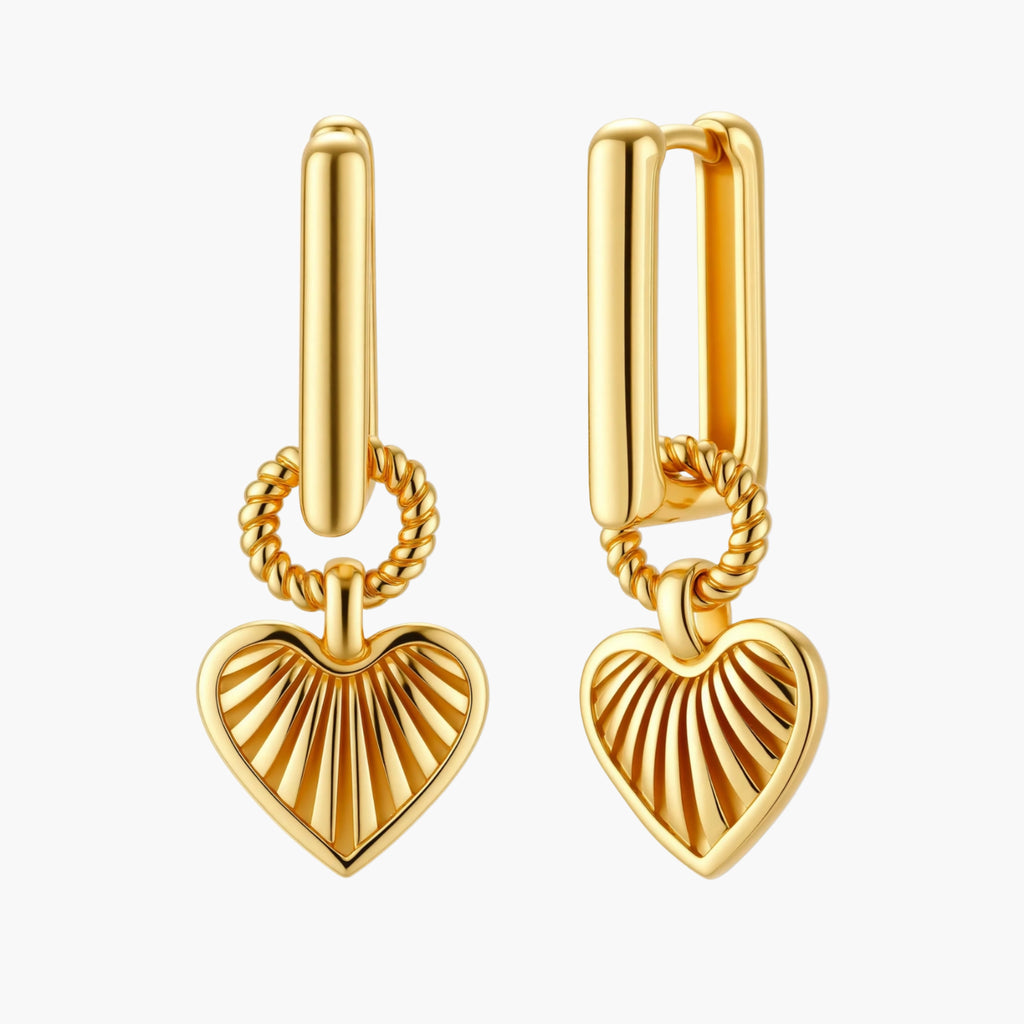 Gold-plated huggie earrings with textured heart charms featuring radiating sunburst patterns on white background.