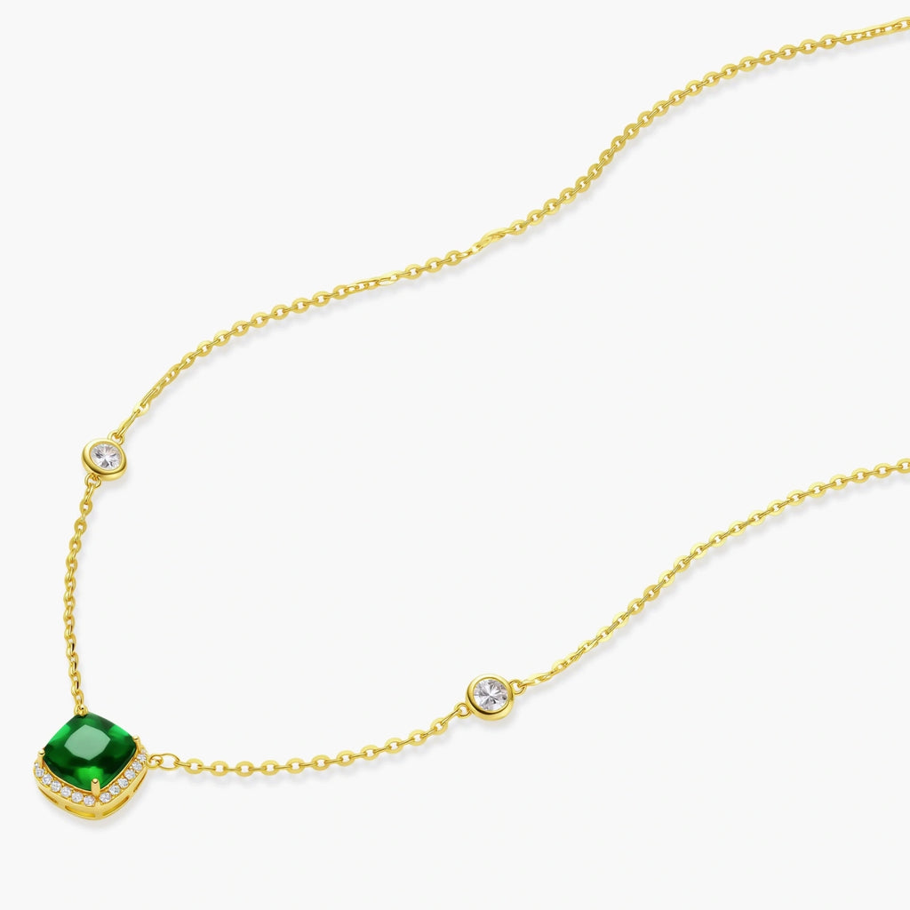 Delicate gold chain necklace featuring square emerald pendant with crystal halo and station accents