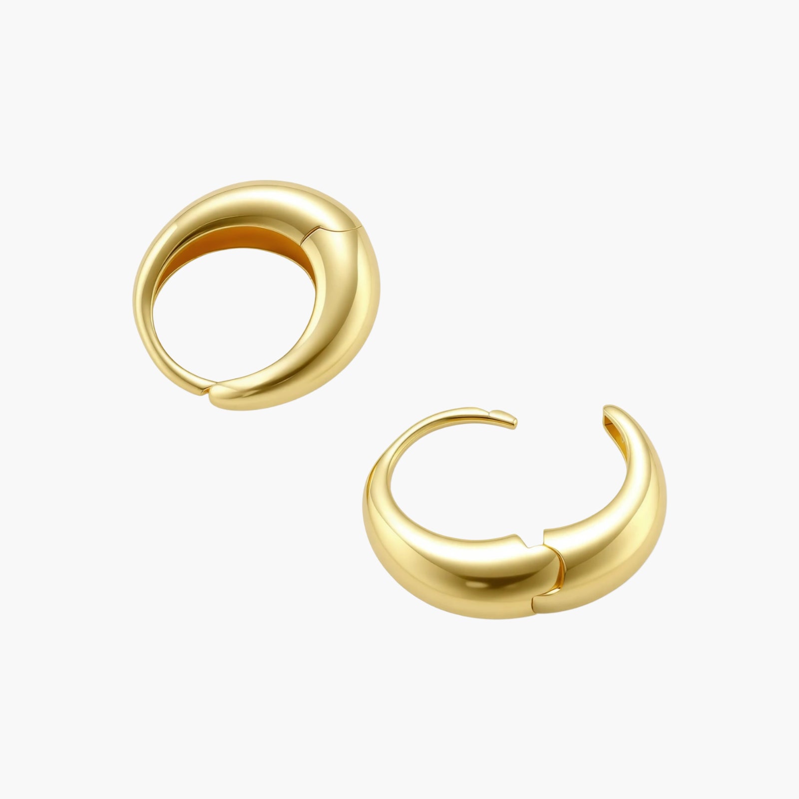 Chunky gold-plated sterling silver huggie hoop earrings with hinged closure mechanism on cream background.