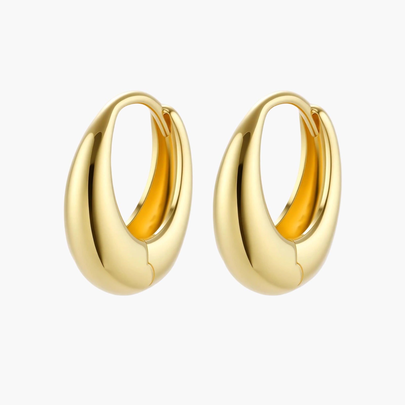 Chunky gold-plated sterling silver huggie hoop earrings with hinged closure mechanism on cream background.