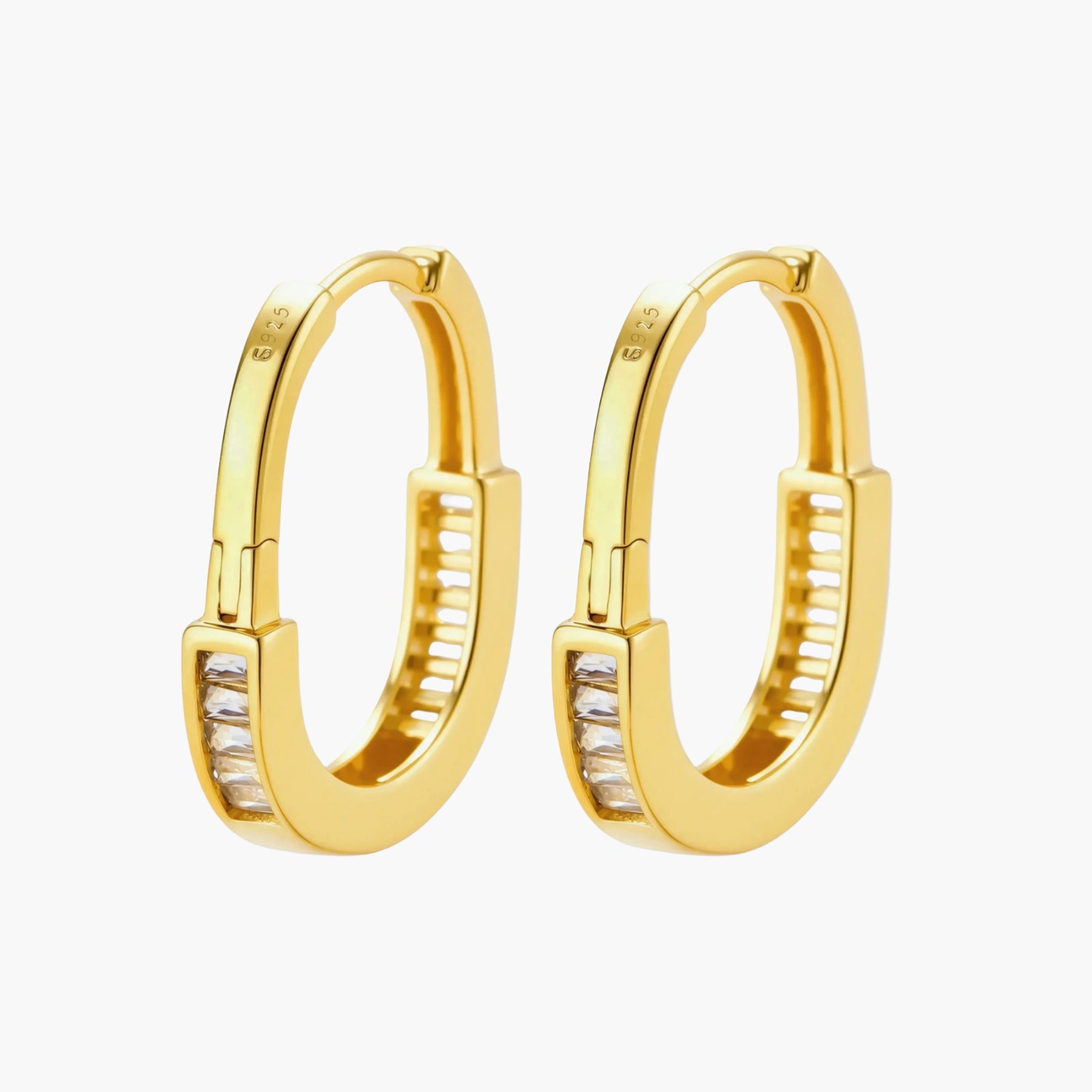 Close-up of gold-plated sterling silver huggie hoop earrings featuring rectangular cubic zirconia stones on neutral background.