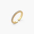 Close-up of adjustable gold-plated ring with continuous row of round zirconia stones on neutral background.