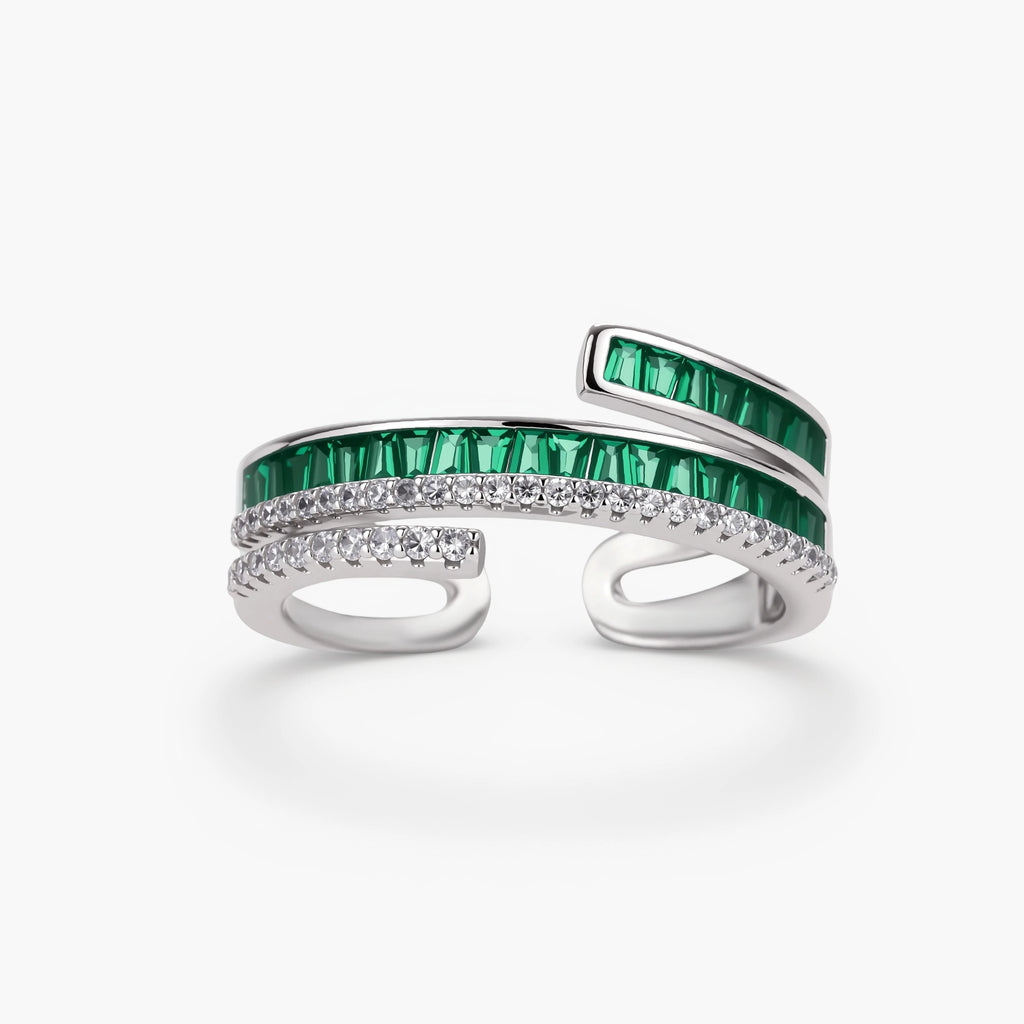 Modern adjustable ring with green baguette stones and clear crystals in parallel bands on white background.