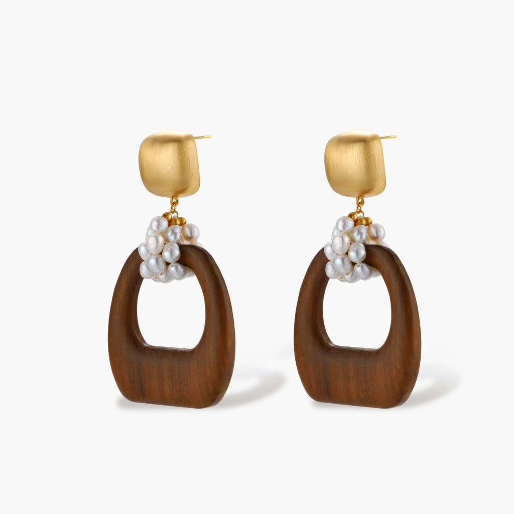 Gold-plated stud earrings with pearl clusters and organic brown wooden hoops on cream background