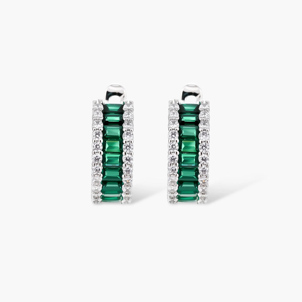 White gold plated jewelry set with emerald green rectangular stones and clear crystals in geometric rows on white background.