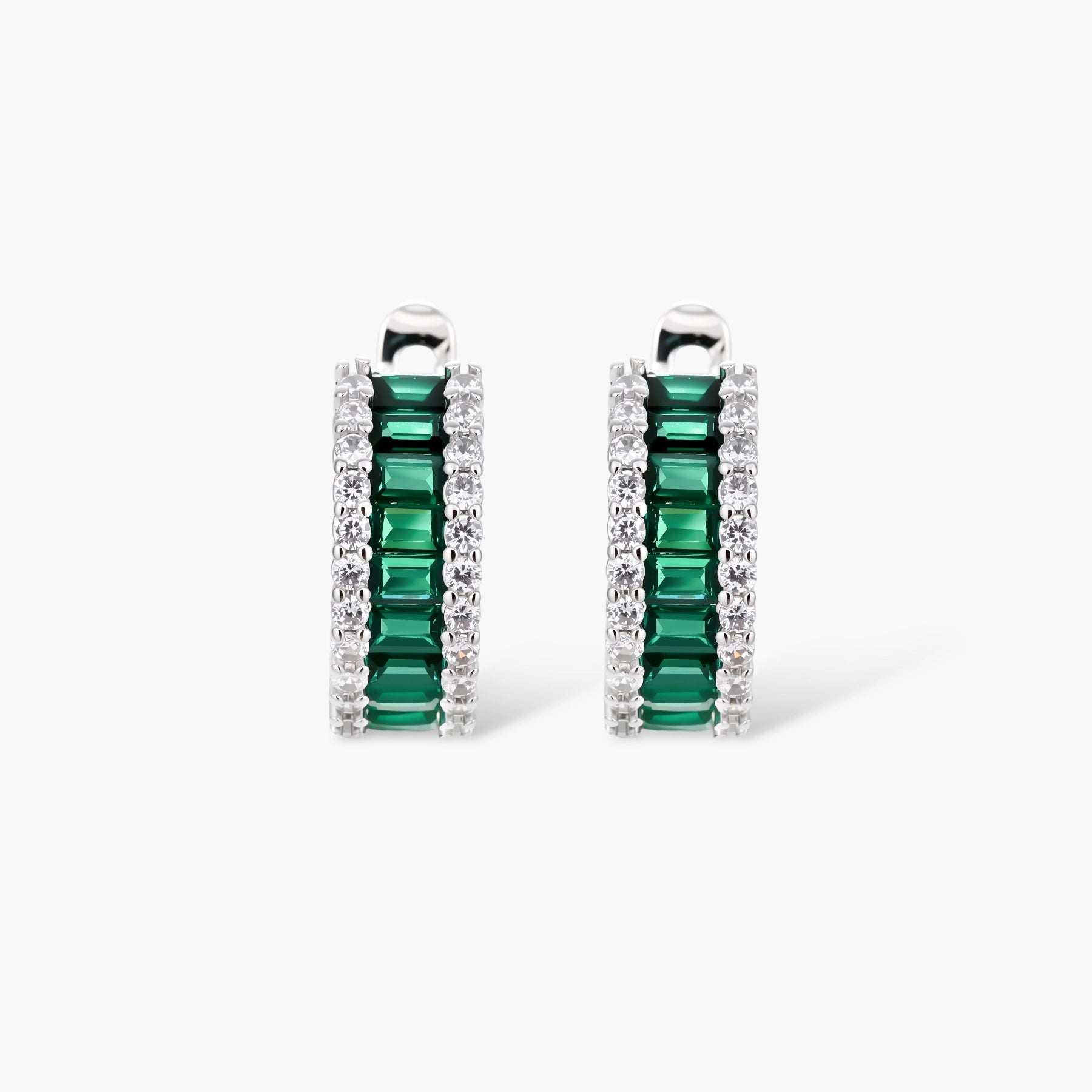 White gold plated jewelry set with emerald green rectangular stones and clear crystals in geometric rows on white background.