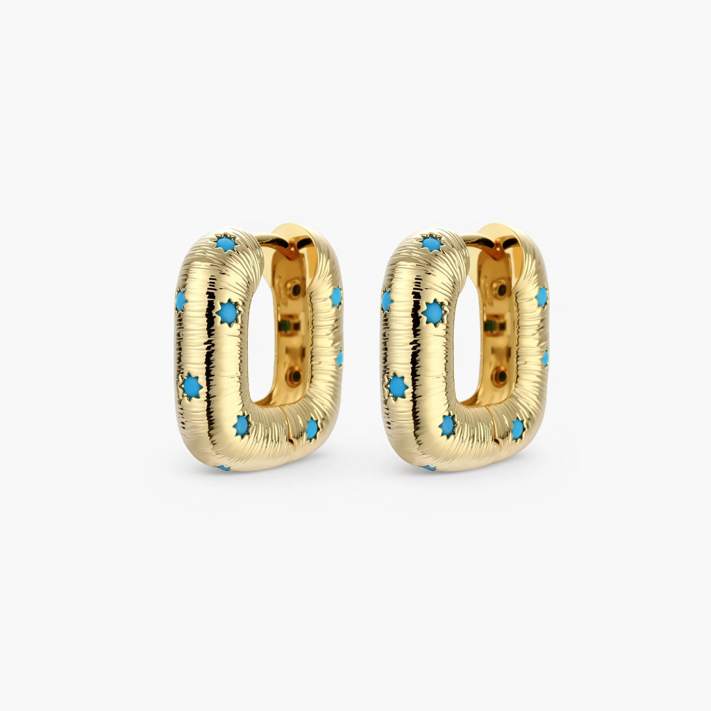 Gold-plated huggie hoop earrings with blue star inlays and textured surface, shown against white background.