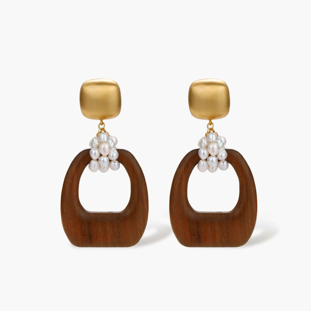 Gold-plated stud earrings with pearl clusters and organic brown wooden hoops on cream background