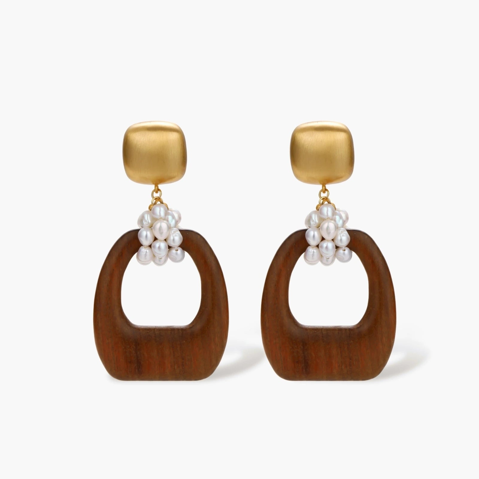 Gold-plated stud earrings with pearl clusters and organic brown wooden hoops on cream background