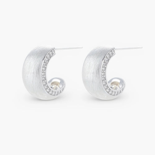 Close-up of small silver-plated hoop earrings with brushed texture and a row of sparkling zircon crystals on white background