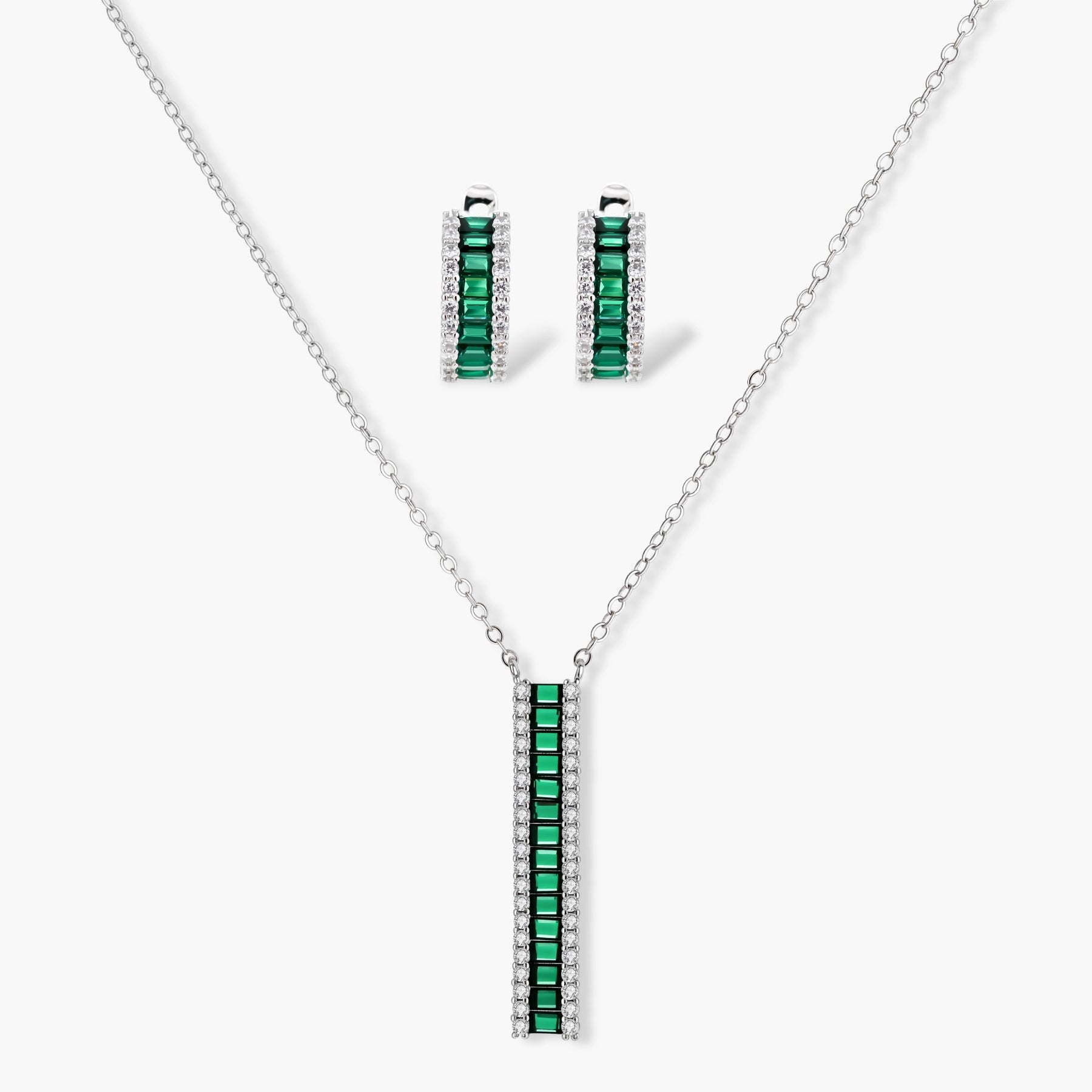 White gold plated jewelry set with emerald green rectangular stones and clear crystals in geometric rows on white background.