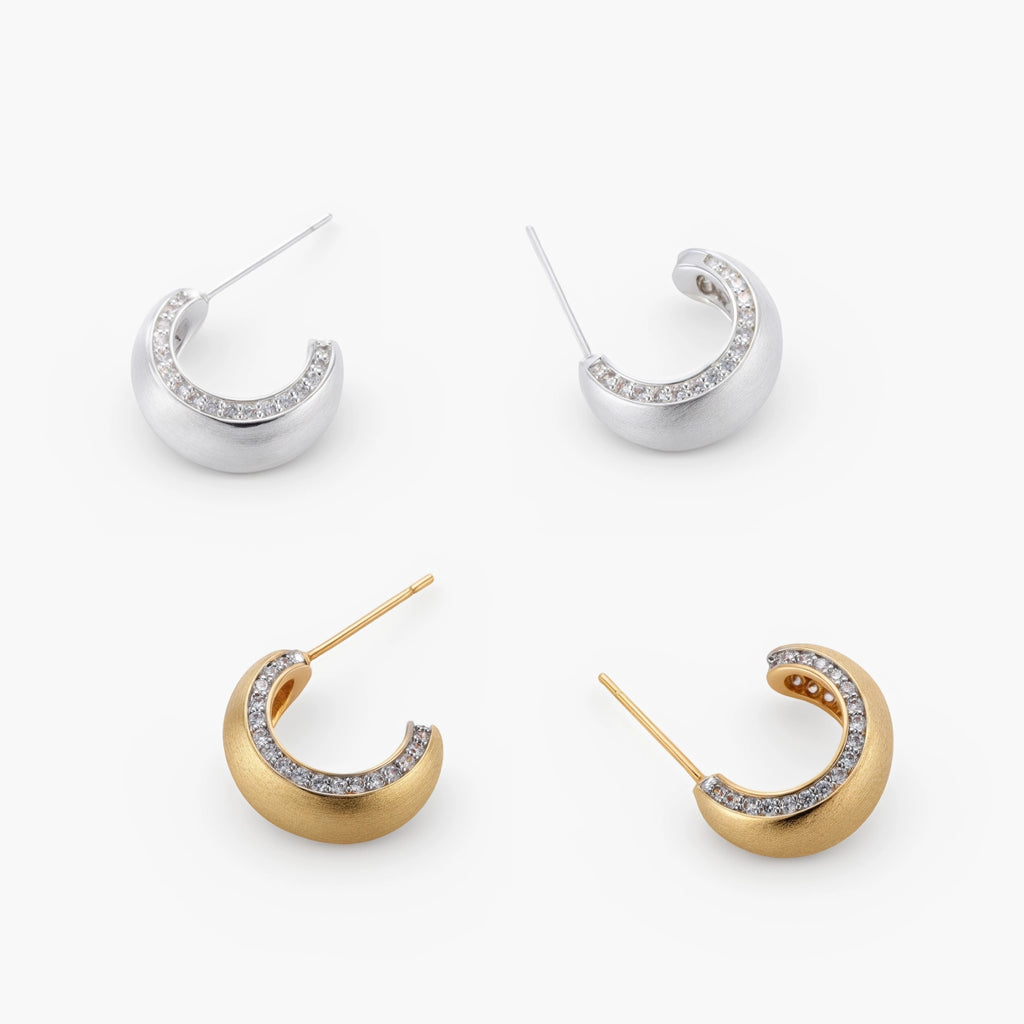 Close-up of small silver-plated hoop earrings with brushed texture and a row of sparkling zircon crystals on white background