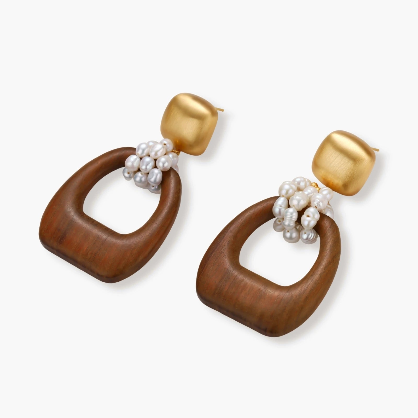 Gold-plated stud earrings with pearl clusters and organic brown wooden hoops on cream background