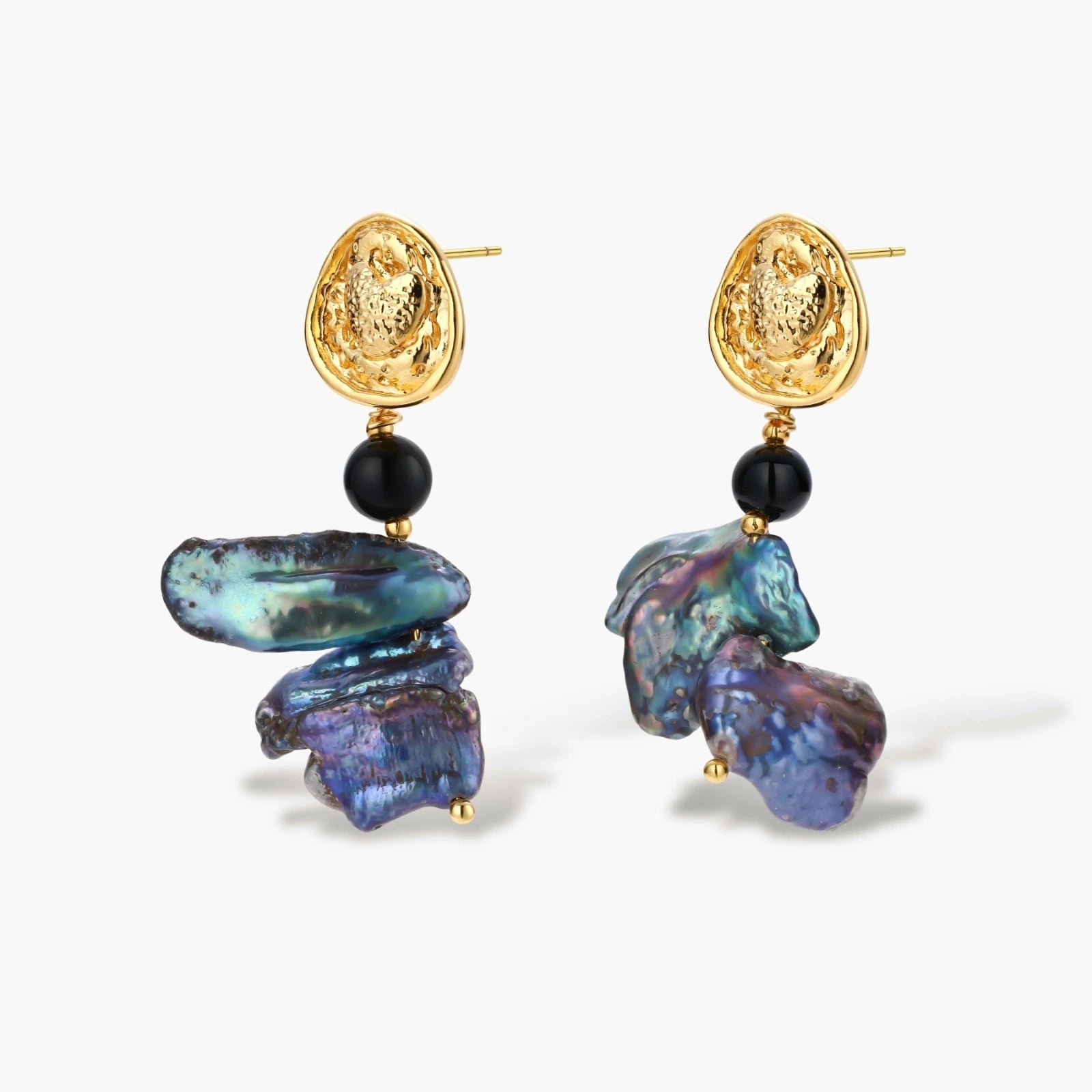 Ornate gold-plated drop earrings with black beads and iridescent blue-purple baroque pearls against white background.