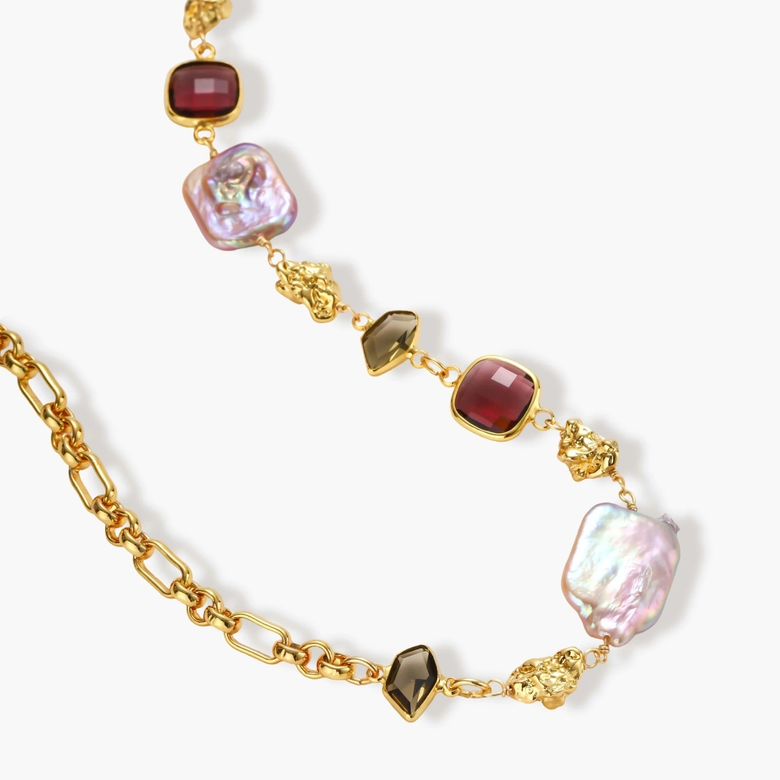 18k gold-plated chain necklace with iridescent baroque pearls and burgundy gemstones on white background.